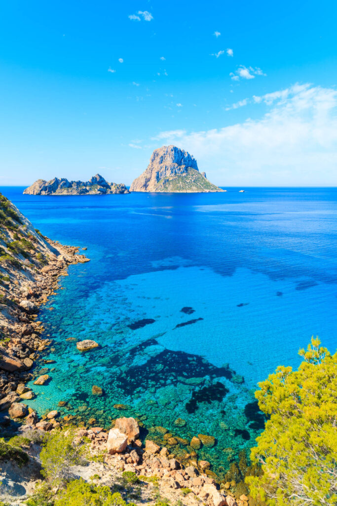 View of Cala d'Hort bay with beautiful azure blue sea water and Es Vedra island in distance, Ibiza island, Spain